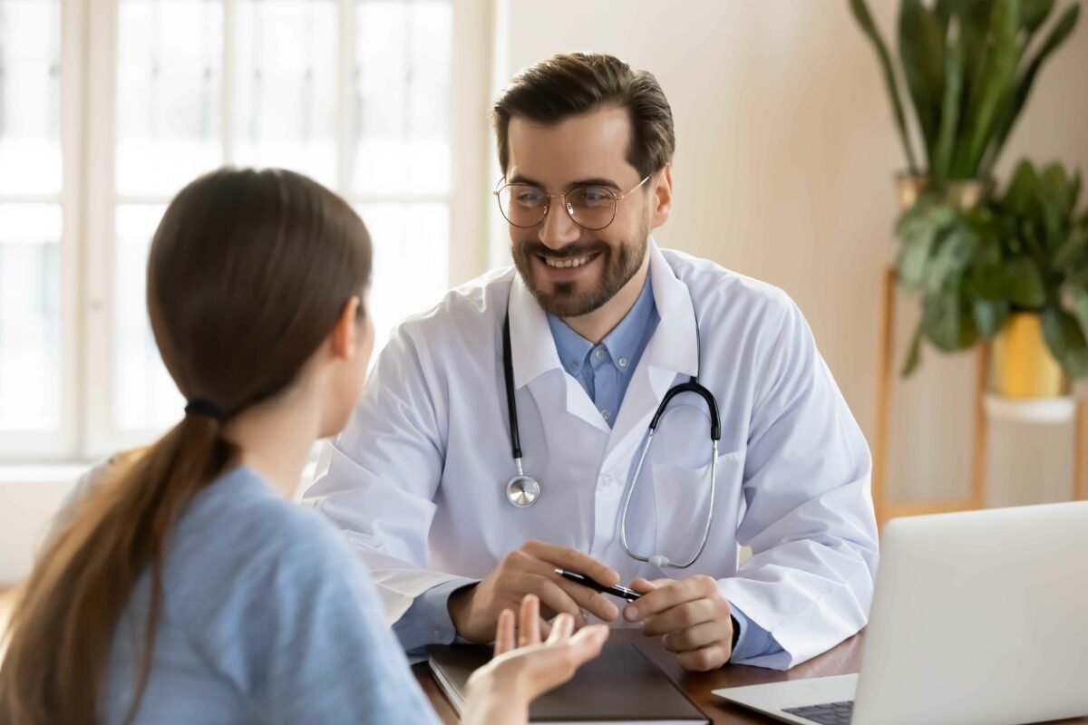 smiling young male doctor listening to woman at meeting